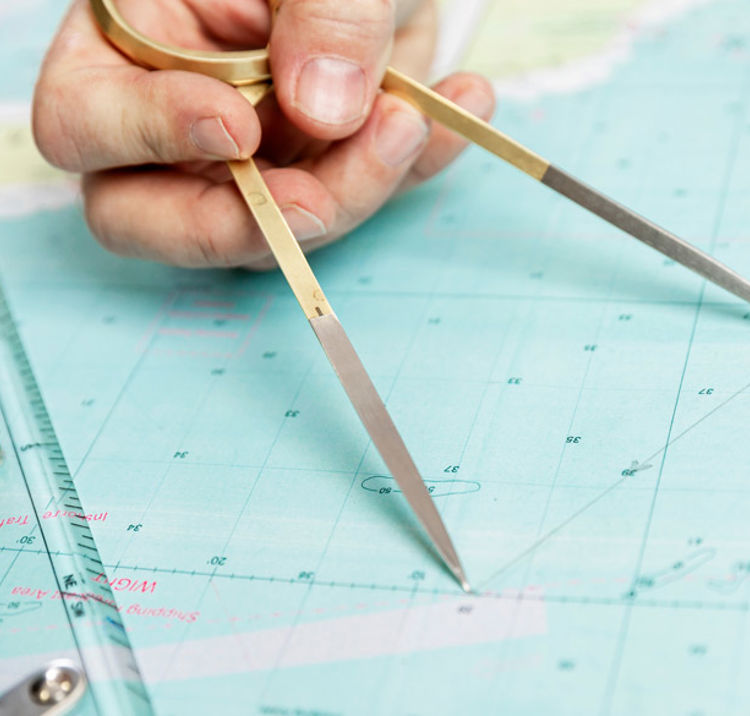 close up of someone measuring distance on a sea chart tool