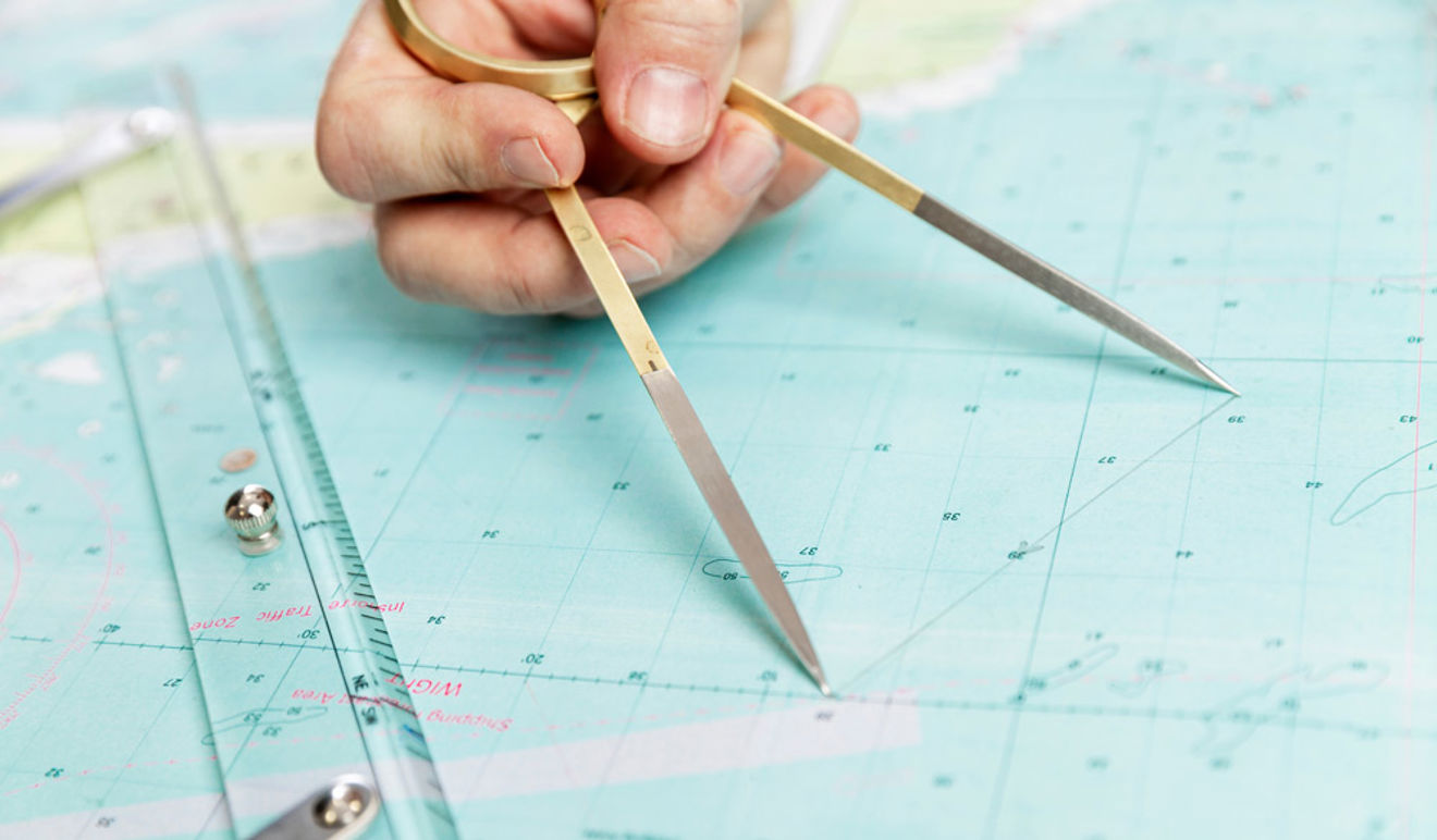 close up of someone measuring distance on a sea chart tool