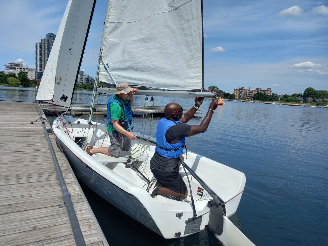 two mean in a boat preparing to sail a dinghy out to sea