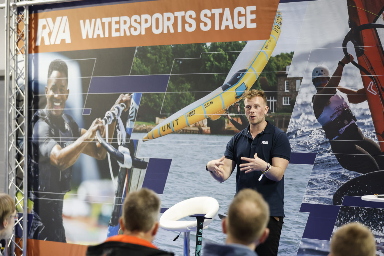 	Image of a young man speaking on the stage from around the 2023 RYA Dinghy &amp; Watersports Show
