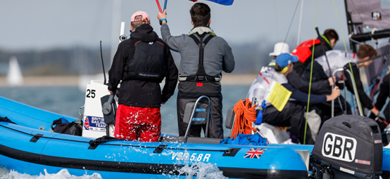 A image with two men on a boat with one being a umpire holding a red flag