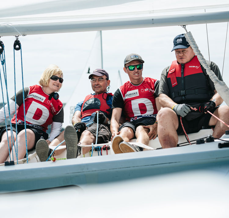 Group of sailors sitting on the edge of their boat