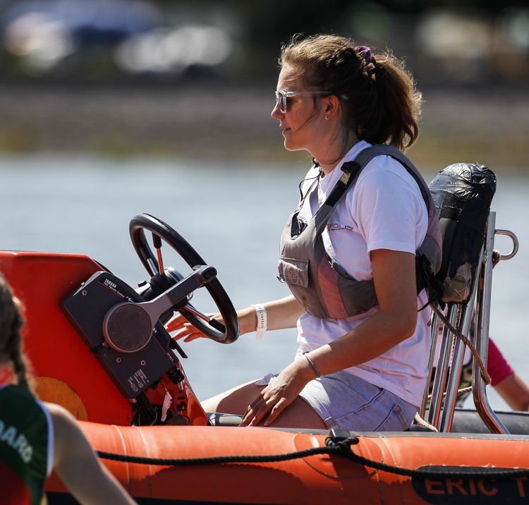 close up of woman steering powerboat, wearing lifejacket and sunglasses