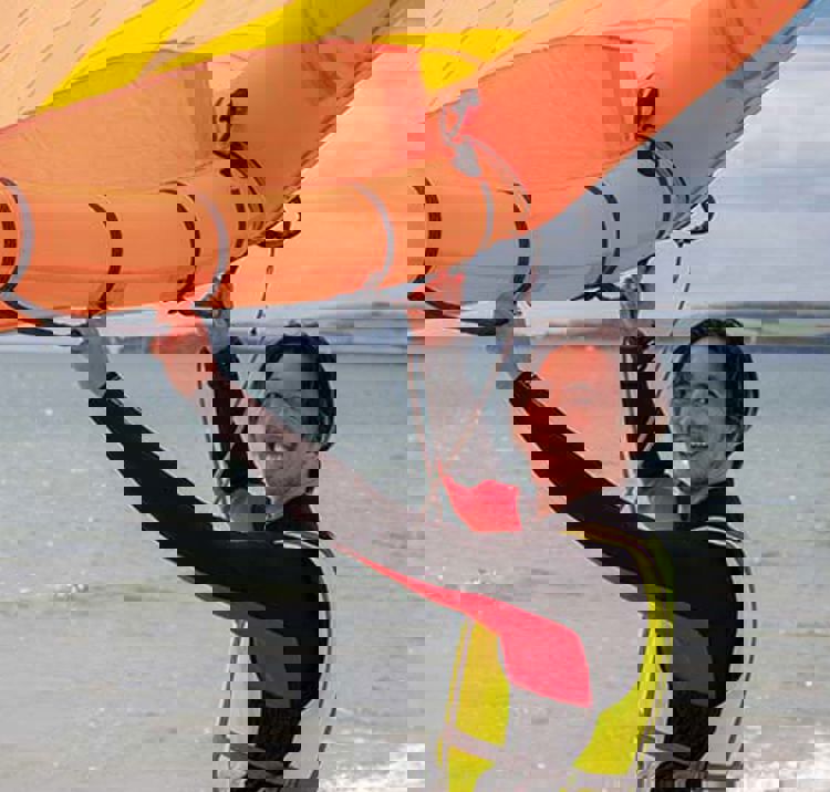 person standing on shore holding a wing up in the air