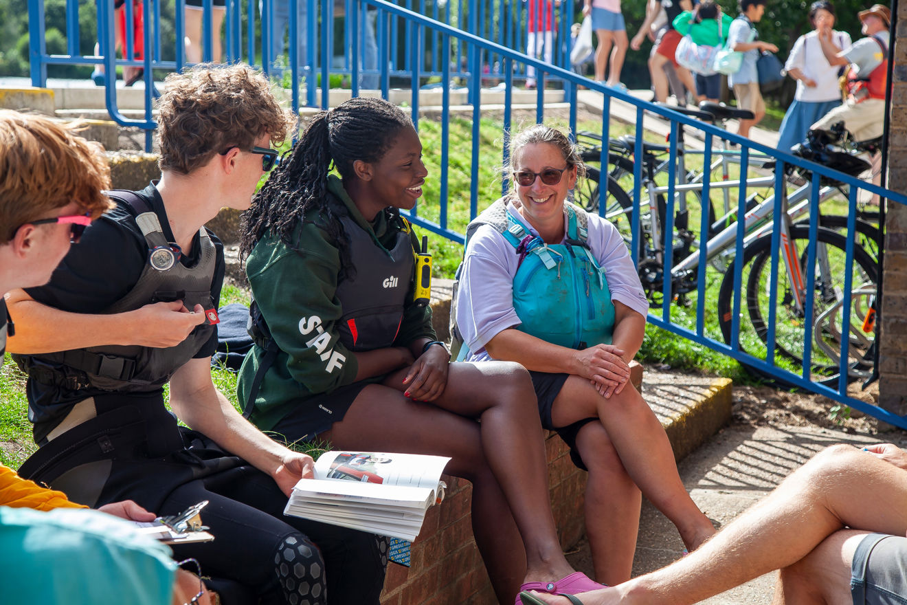 	young women sitting on wall talking to a group of people