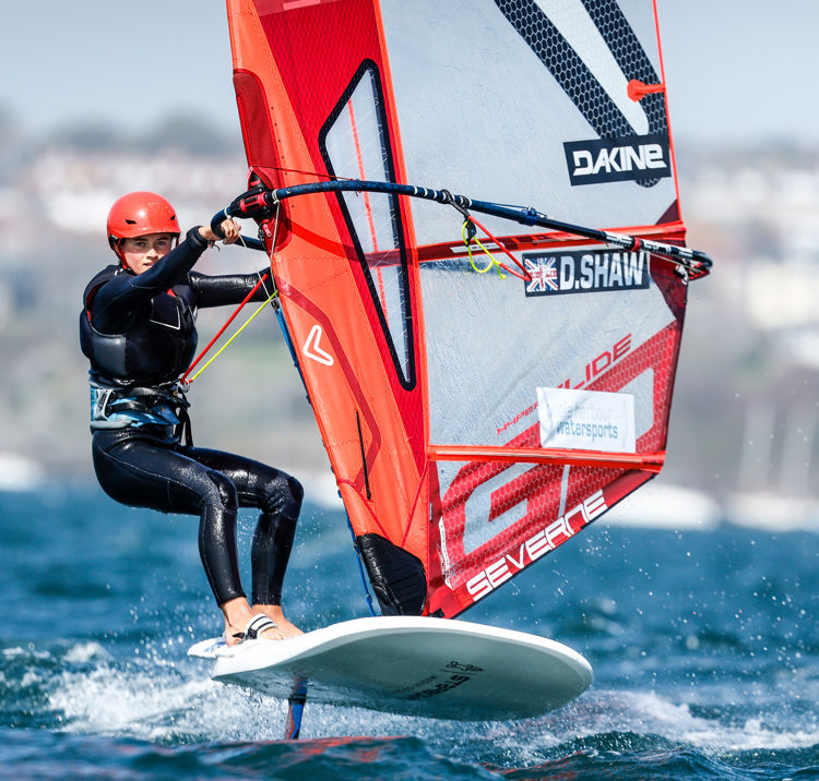 Long shot of woman windsurf foiling with orange sail