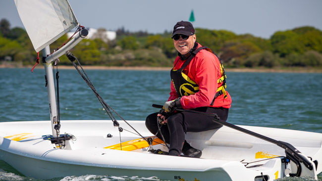 sailor in a dinghy smiling at the camera