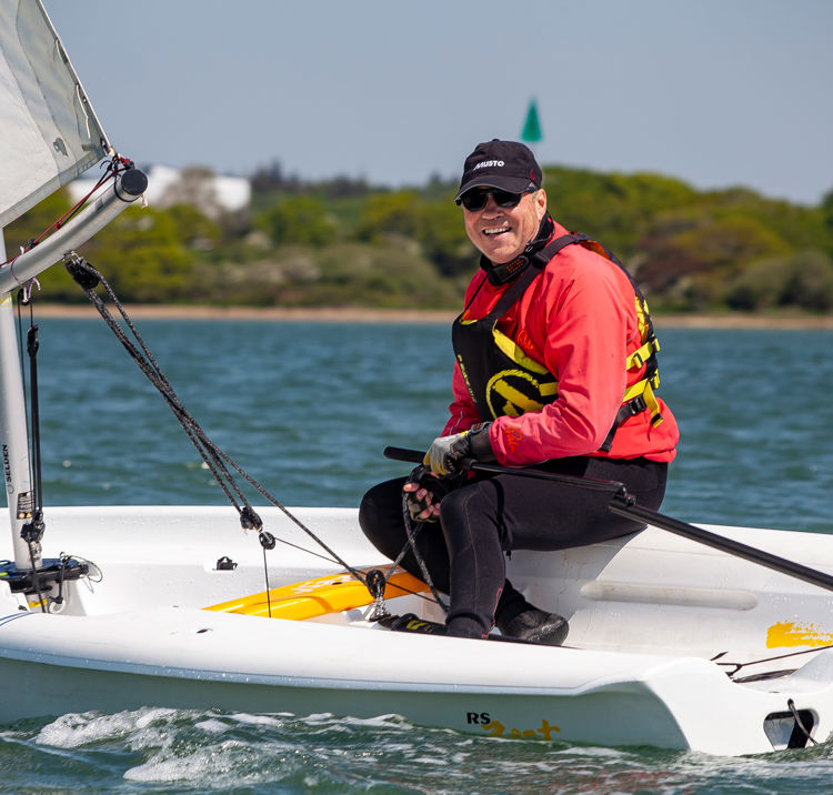 sailor in a dinghy smiling at the camera