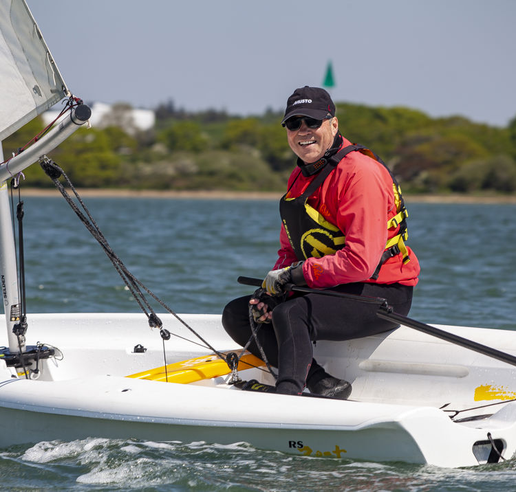 sailor in a dinghy smiling at the camera