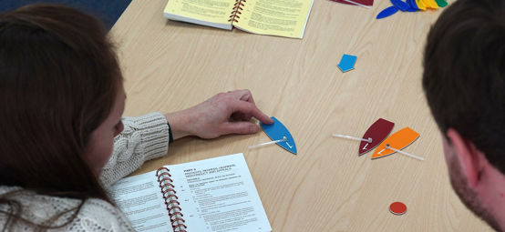 Two people engaged in a classroom based sailing training activity