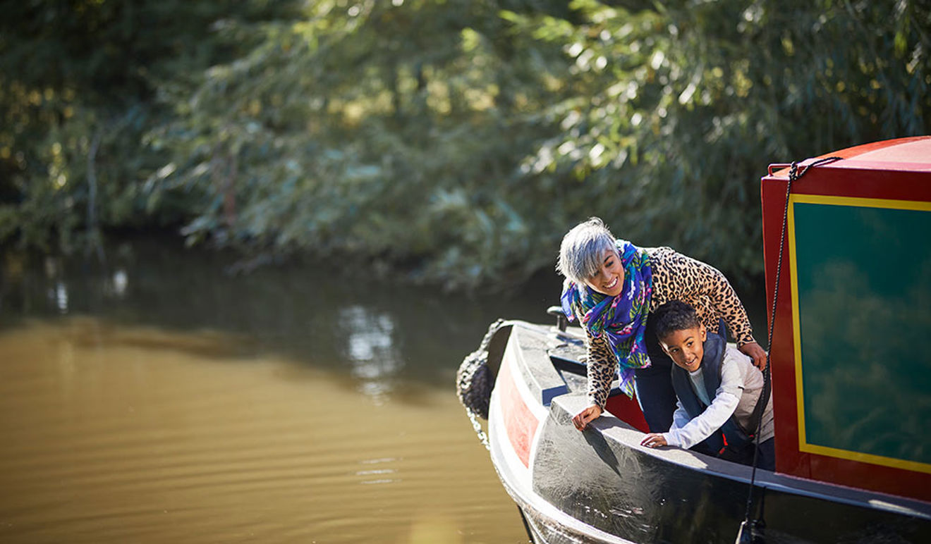 Mother and son leaning over the side of a narrowboat.