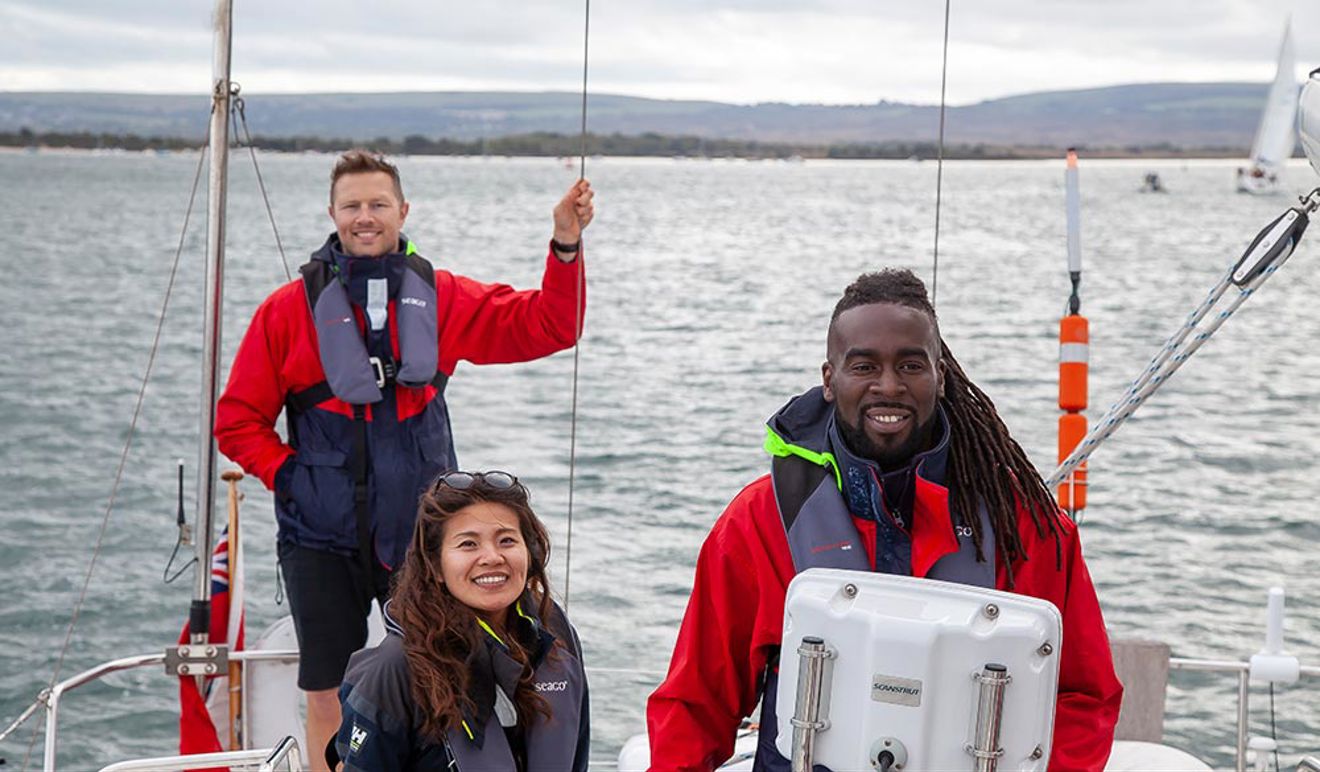 two men and one woman on a yacht smiling