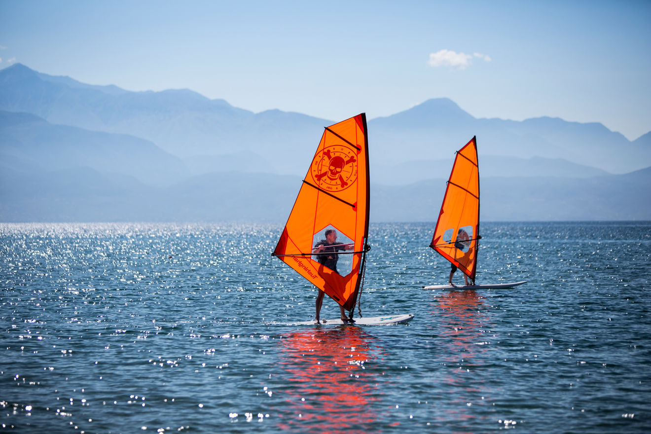 two people windsurfing on calm water