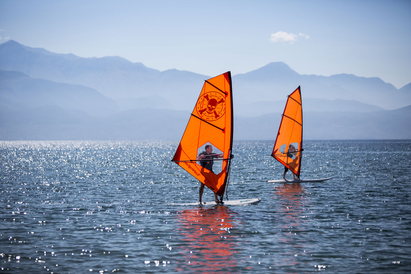 two people windsurfing on calm water