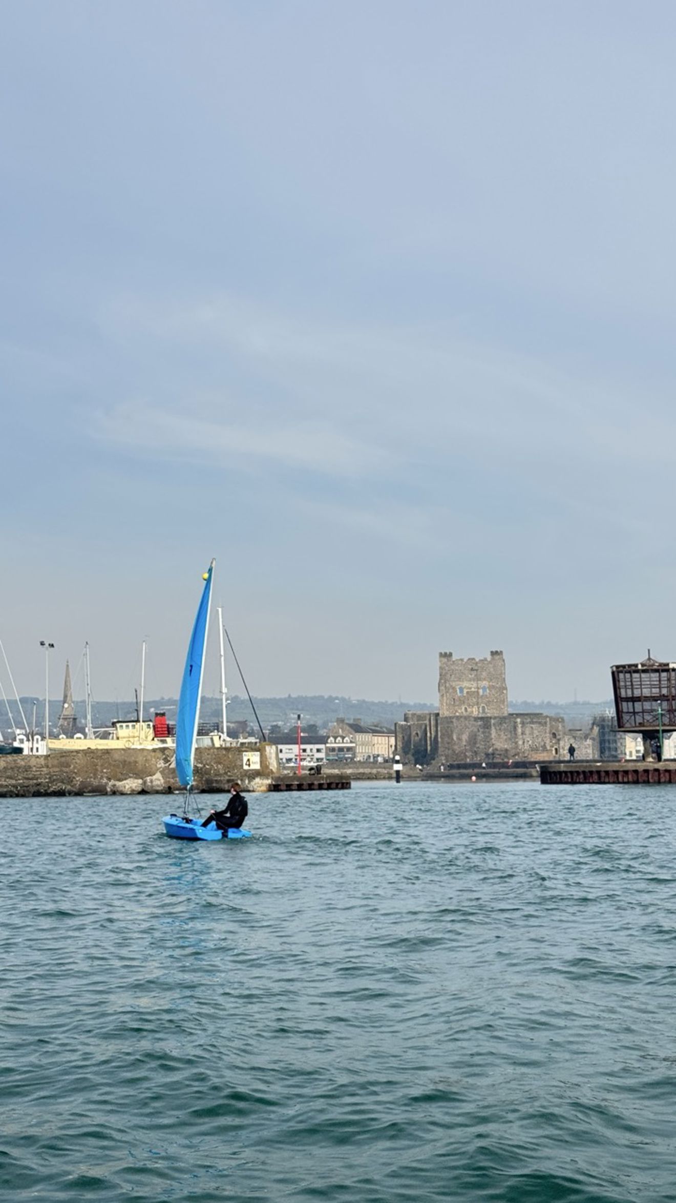 Instructor sailing an RS Quba in front of Carrickfergus Castle