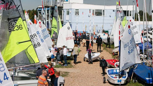 Multiple boats and dinghies on the shore with people walking around them