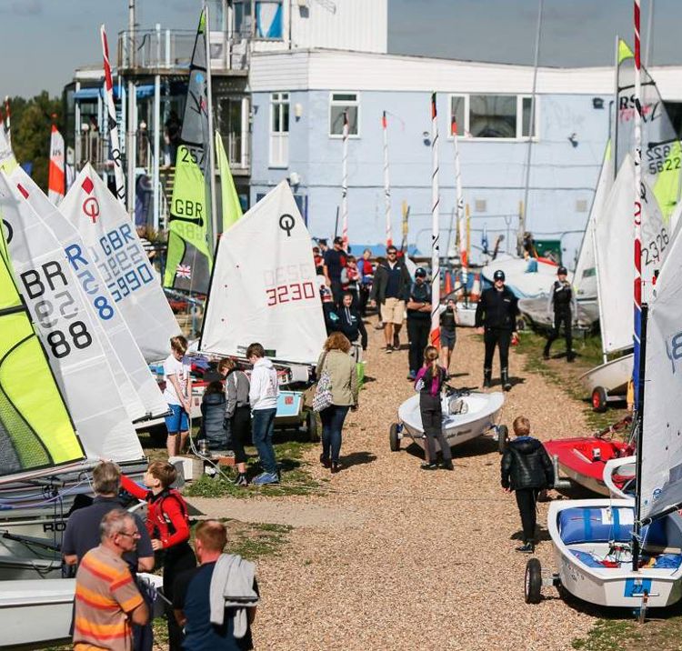 Multiple boats and dinghies on the shore with people walking around them