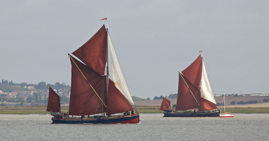 Classic sailboats cruising a river