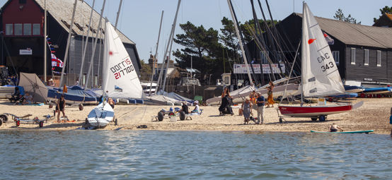 	a wide angle shot of a sailing club preparing sailing boats on a sunny day to go sailing.