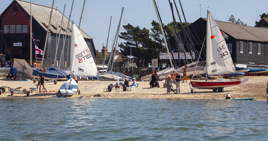 	a wide angle shot of a sailing club preparing sailing boats on a sunny day to go sailing.