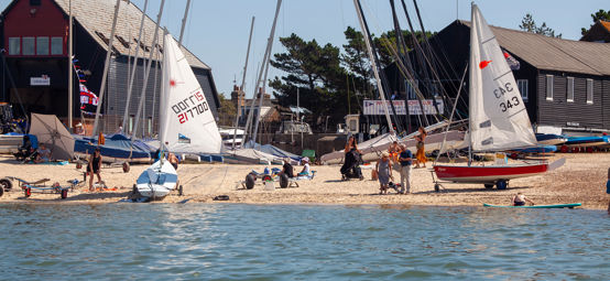 	a wide angle shot of a sailing club preparing sailing boats on a sunny day to go sailing.