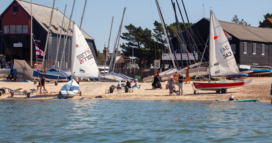 	a wide angle shot of a sailing club preparing sailing boats on a sunny day to go sailing.