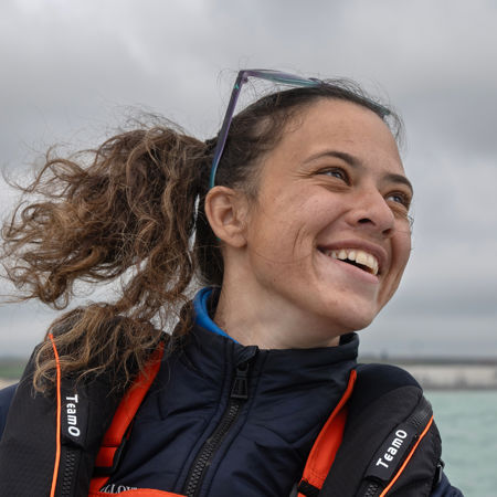 Mid shot of female sailor smiling with the sea behind her
