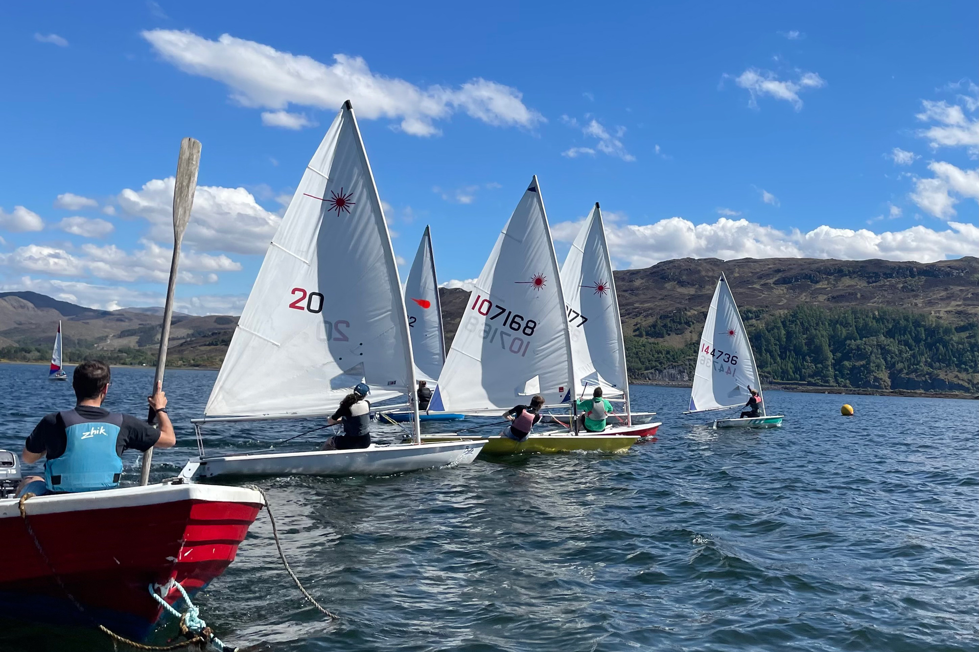Long shot of five sailing boats with hills in the background