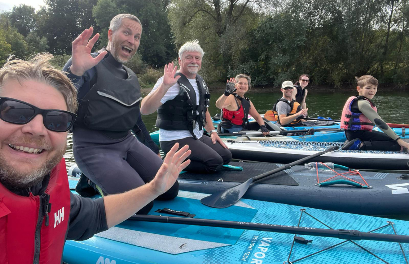 Adults and children smiling for a selfie on their paddleboards at Northampton Sailing Club