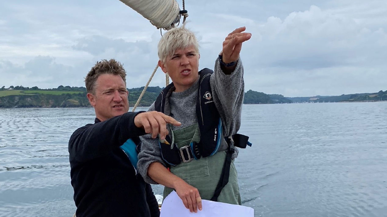 Mid shot of a man and woman pointing at the water from their boat 