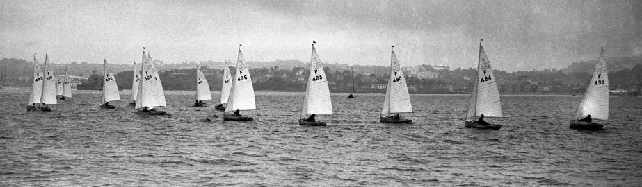 Black and white photo of wooden dinghies preparing for a race