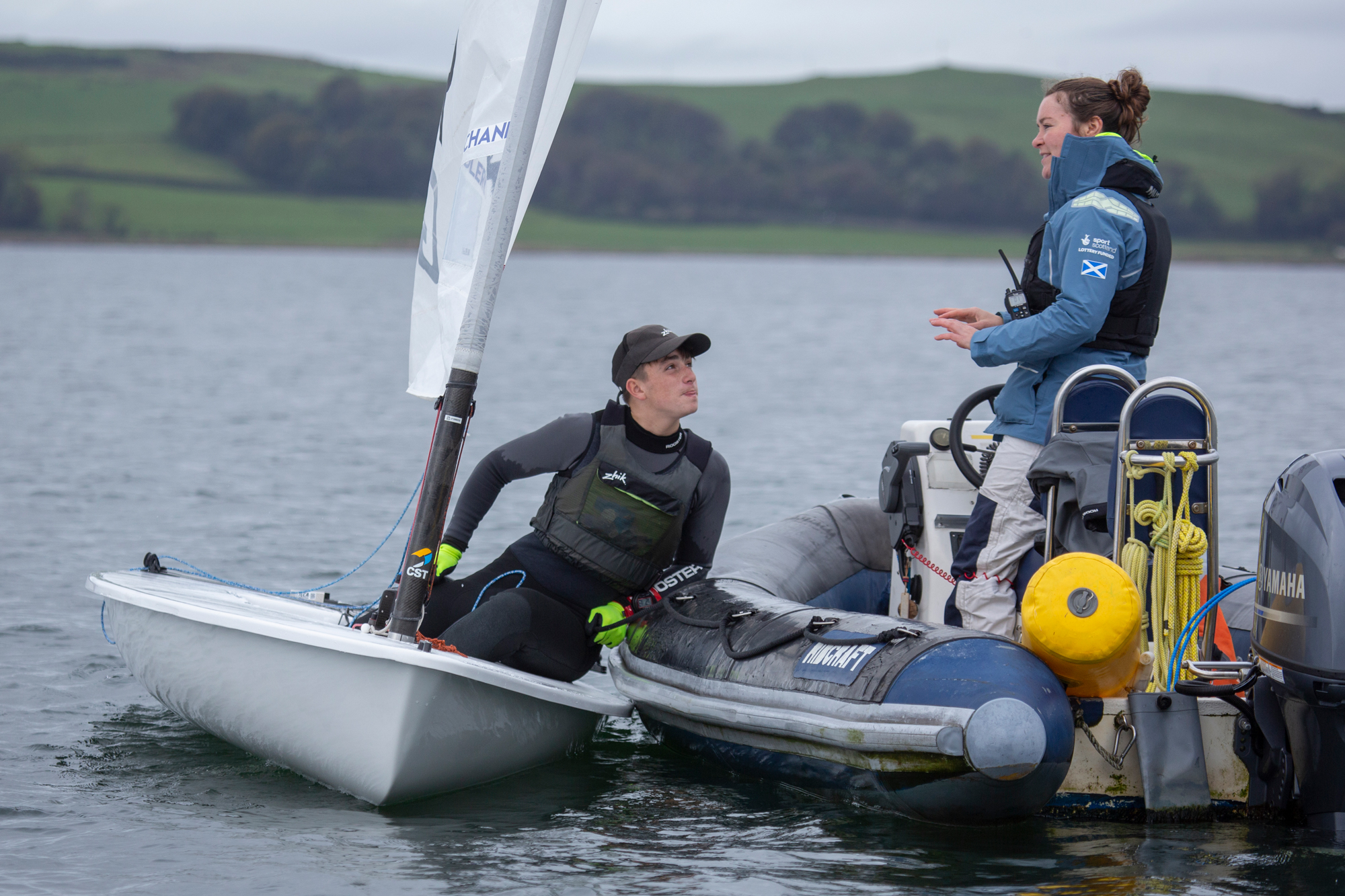 Mid shot of two sailors communicating on their sailboat and powerboat