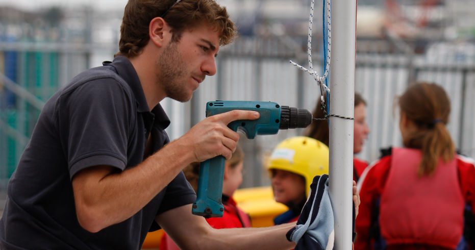 A volunteer drilling a boat mast