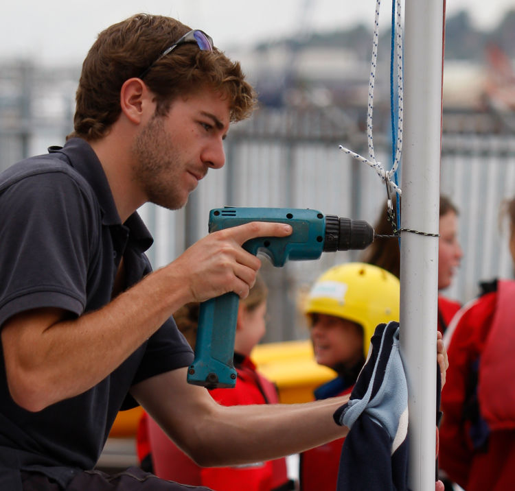 A volunteer drilling a boat mast