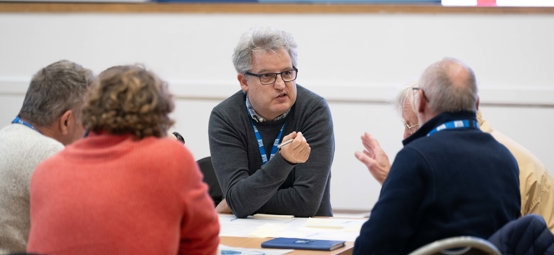 Mid shot of attendees at a Connected Conference discussing at a table