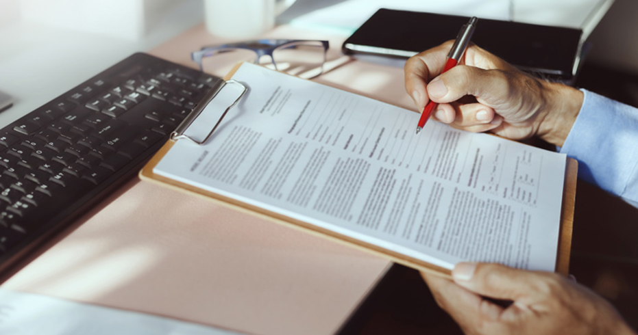 person signing form on clipboard