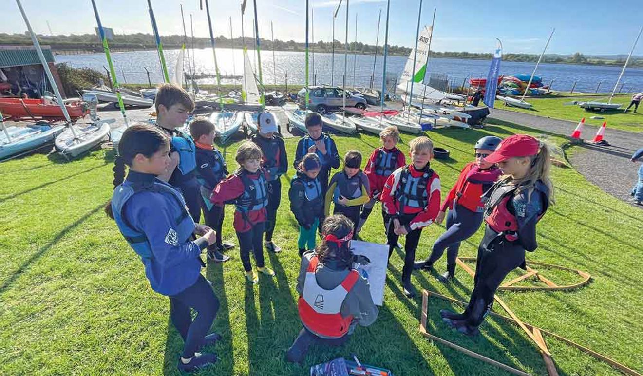 group of children on shore listening to instructor