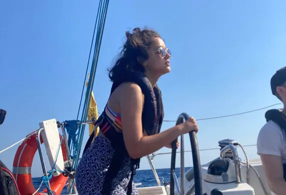 A lady steering a Barcelona Watersports yacht on the water against a very blue sky