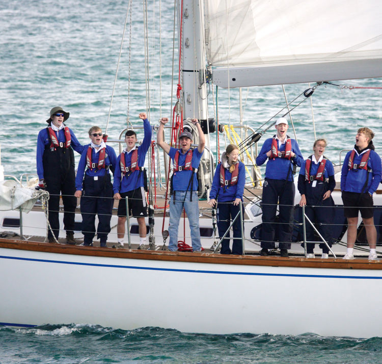 group of people lined up along the side of a yacht in the ocean ASTO cowes small ships race