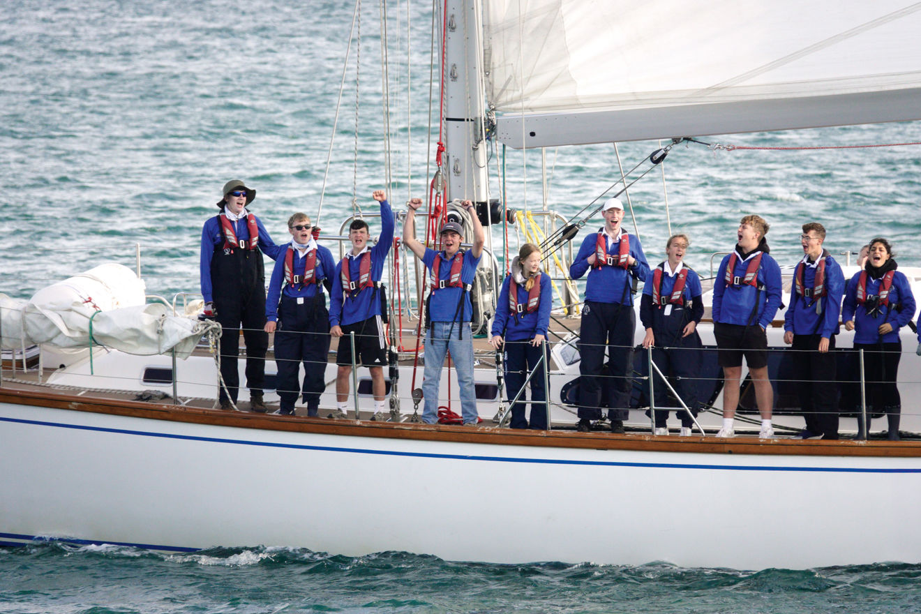 group of people lined up along the side of a yacht in the ocean ASTO cowes small ships race