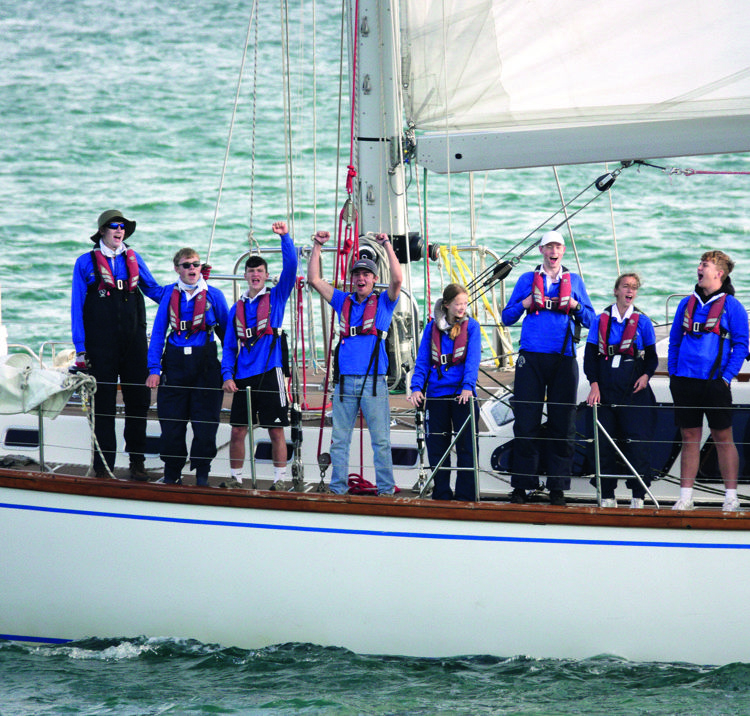 group of people lined up along the side of a yacht in the ocean ASTO cowes small ships race