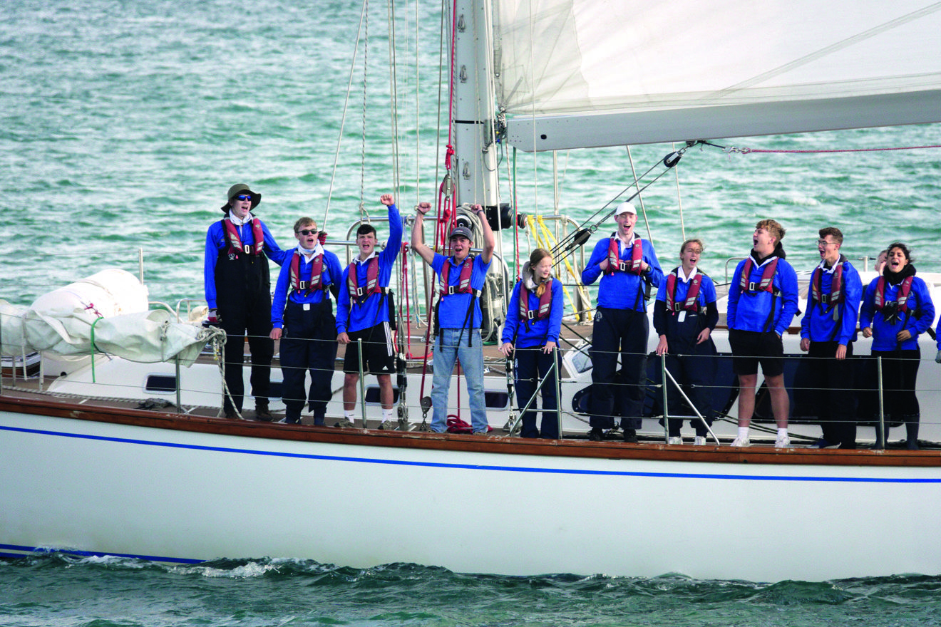 group of people lined up along the side of a yacht in the ocean ASTO cowes small ships race