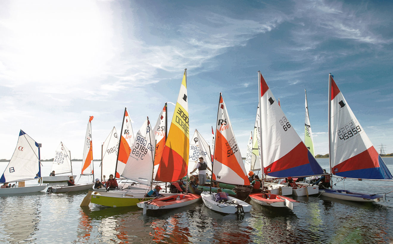 Wide shot of a junior dinghy racing fleet in the sunshine