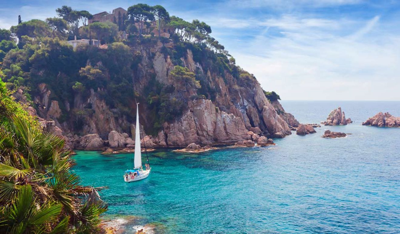 sailing yacht anchored off the coast in clear blue waters 