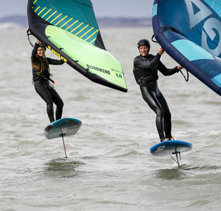 two people wing foiling on the open water
