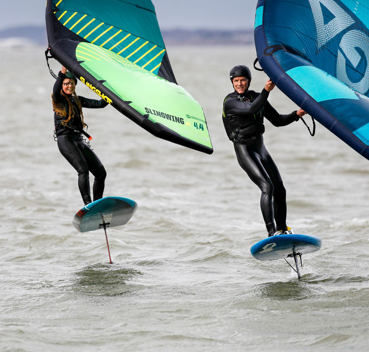 two people wing foiling on the open water