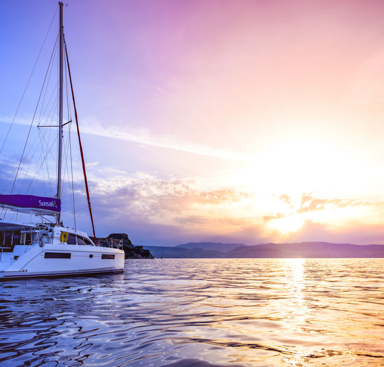 Sunsail catamaran in the ocean with a beautiful sunset