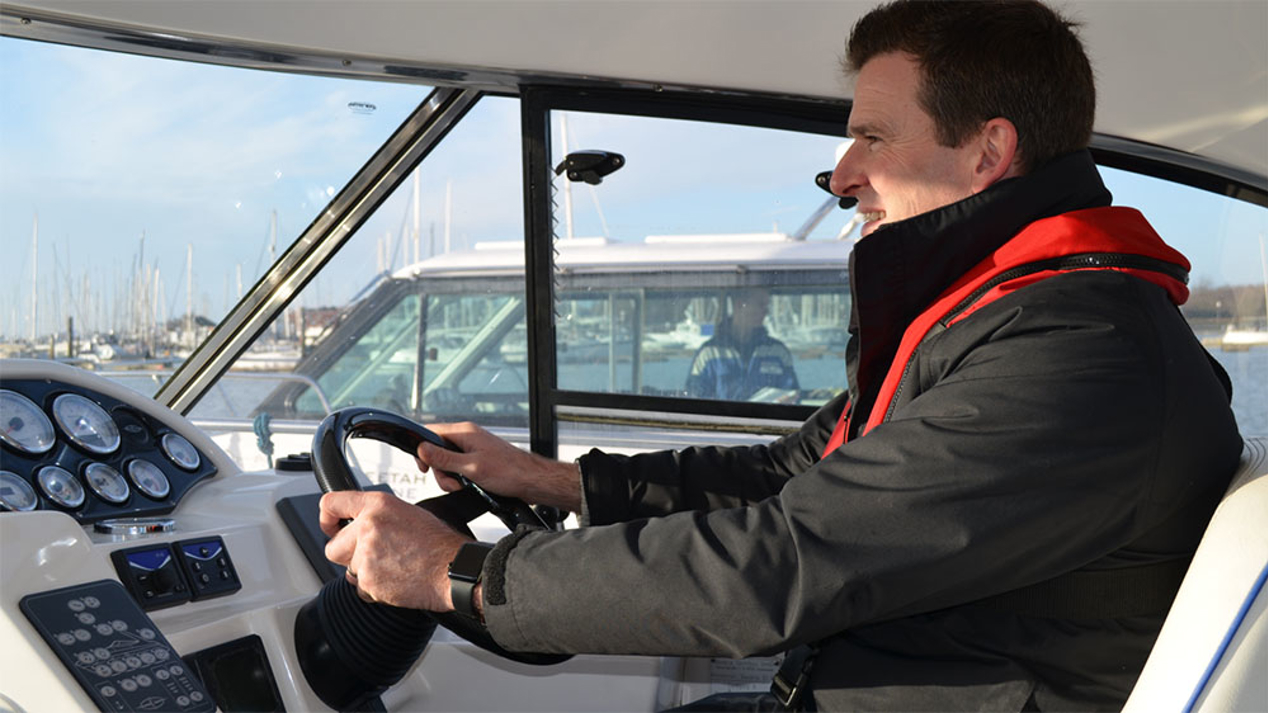 Man at the helm of his motor cruiser smiling at the view