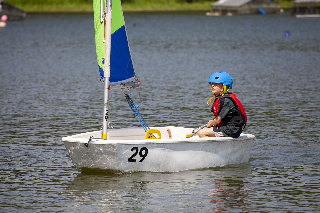 Wide shot of child sailing their single hander dinghy 