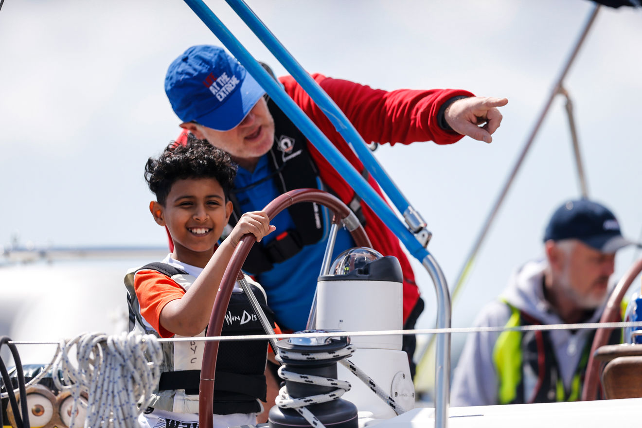 boy on the helm of boat with instructor